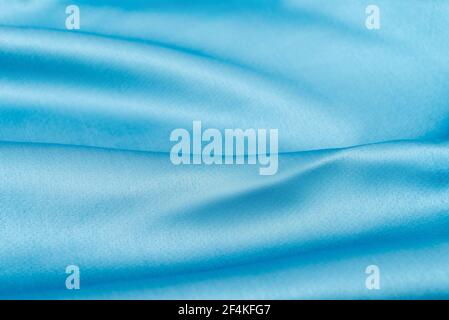 Beautiful wavy silk fabric in sky blue color. Smooth elegant luxury cloth fabric texture. Abstract background design. Copy space, selective focus Stock Photo