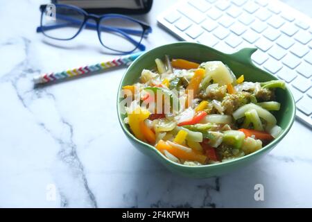 bowl of fresh salad on office desk Stock Photo