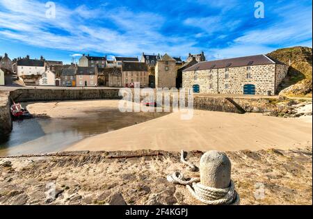 PORTSOY OLD HARBOUR MORAY FIRTH ABERDEENSHIRE SCOTLAND OLD WAREHOUSES A SANDY BEACH AT LOW TIDE AND TWO RED BOATS Stock Photo