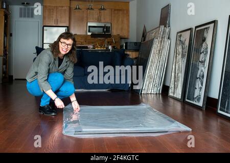 Peekskill, New York, USA. Female artist, Melinda Hunt, showing the artwork on her Hart Island Project, while giving an interview inside her studio. Stock Photo