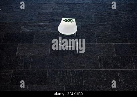 a white chair indoors on black tile floor Stock Photo