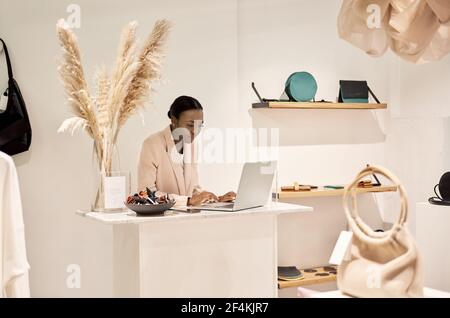 African American entrepreneur working on a laptop in her boutique Stock Photo