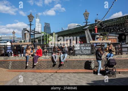 Londoner's sit out along the Thames River bankside at Southwark enjoying the early Spring sunshine during their lunchtime, England, United Kingdom Stock Photo