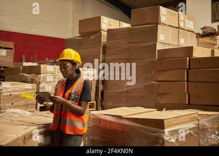 Young African female warehouse worker doing inventory using a tablet Stock Photo