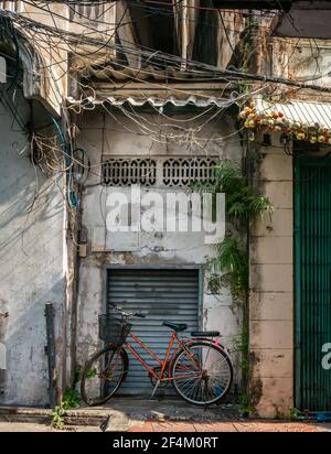 Parked bicycle on sidewalk in front of folding steel door next to door of old house. Selective focus. Stock Photo