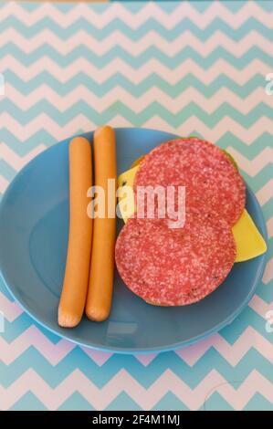 POZNAN, POLAND - Aug 18, 2017: Two sausages next to bread with cheese and salami on a blue plate in soft focus Stock Photo