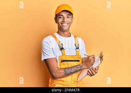 Young handsome african american man wearing courier uniform holding clipboard smiling with a happy and cool smile on face. showing teeth. Stock Photo