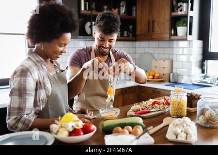 Happy black couple cooking and tasting healthy food in kitchen Stock Photo