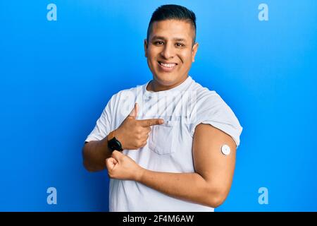 Young latin man using glucose meter button smiling happy pointing with hand and finger Stock Photo