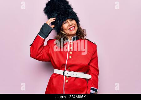 Middle age beautiful wales guard woman wearing traditional uniform over pink background confuse and wonder about question. Uncertain with doubt, think Stock Photo