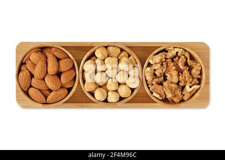 Almons, hazelnuts and walnuts in wooden bowls on white background Stock Photo