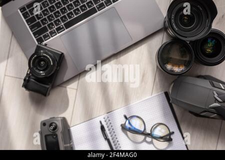 Layout of gadgets top view on a wooden background. Hi tech Travel gadgets, mobile phone, camera, lens, notebook and glasses, laptop. Stock Photo