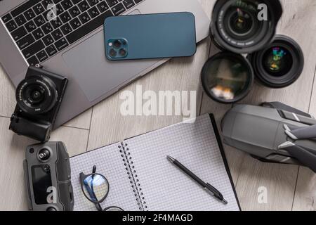 Layout of gadgets top view on a wooden background. Hi tech Travel gadgets, mobile phone, camera, lens, notebook and glasses, laptop. Stock Photo