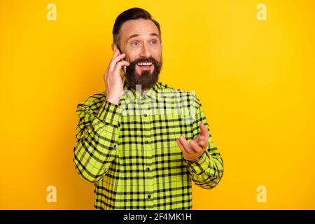 Portrait of attractive cheerful man using device calling friend discussing news isolated over bright yellow color background Stock Photo