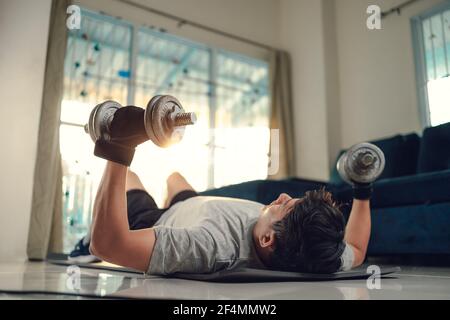Young man use dumbbell exercises chest fly on yoga mat in living room at  home. Fitness, workout and traning at home concept Stock Photo - Alamy
