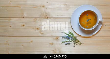 A cup of herbal tea with a flowering thyme. On a light wooden background. Stock Photo