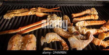 A collection of different kinds of seafood bbq cooking on a grill with  tiger shrimp, Alaskan snow crab and Alaskan king crab Stock Photo