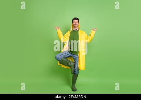 Full size photo of brunet optimistic guy do yoga wear cloak boots isolated on green color background Stock Photo