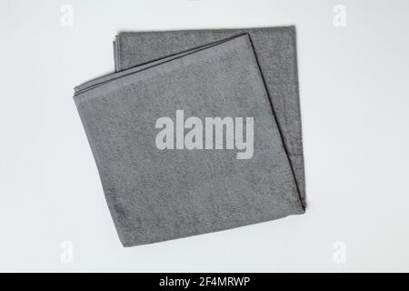 Gray folded towel on a white background. Close-up flat lay top view. Stock Photo