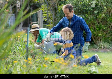 Caucasian father and son in garden watering plants and gardening with their family Stock Photo