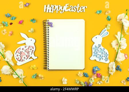 Happy Easter mockup or template, blank paper, notebook on a yellow bakcground with spring flowers.and decorations Stock Photo