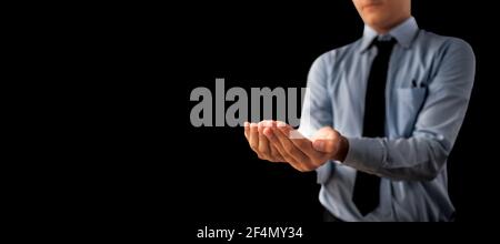 Shot of a unrecognizable man wearing blue shirt black tie and hands in a shape containing something inside it isolated on black background. Stock Photo