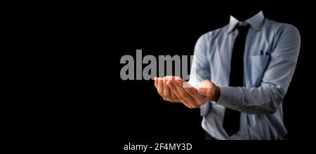Shot of a unrecognizable man wearing blue shirt black tie and hands in a shape containing something inside it isolated on black background. Stock Photo
