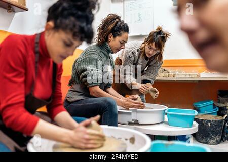 Stock photo of pottery teacher explaining to concentrated woman how to use spinning wheel. Stock Photo