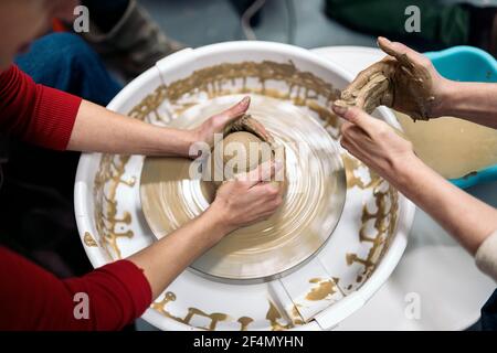 Stock photo of unrecognized person using potter's wheel during pottery class. Stock Photo