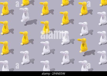 Creative pattern with yellow and white plastic bunny on grey background. Minimalist concept. Isometric layout. Stock Photo