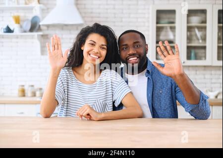 Video chat with an African-American couple, cheerful biracial woman and man looking at the camera and waving hello. Virtual meeting with family or friends, video call during pandemic, webcam view Stock Photo
