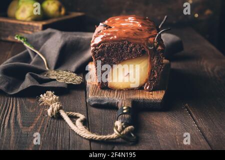 Homemade chocolate cake with pear at rustic wooden background. Brownie with fudge. Stock Photo