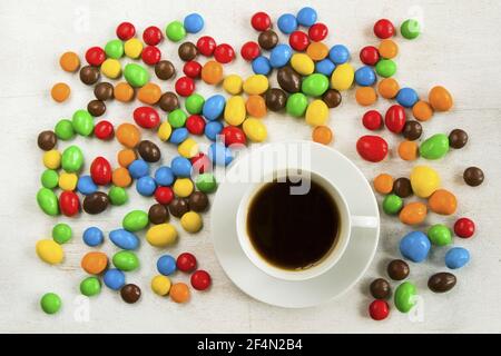 Cup of black coffee surrounded by chocolate candy balls on a white background Stock Photo