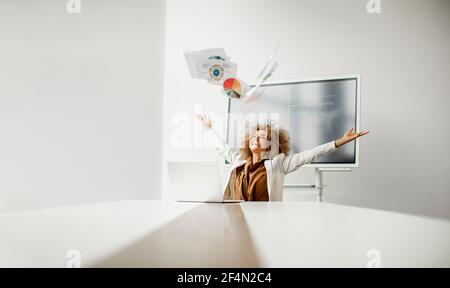 Young African American businesswoman throwing paper in the air after receiving of great news in the modern office Stock Photo