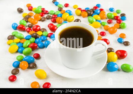 Cup of black coffee surrounded by chocolate candy balls on a white background Stock Photo