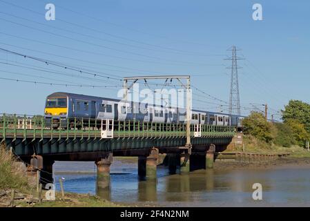 A Class 321 electrical multiple unit number 321318 working a National Express Anglia service crossing the River Stour at Manningtree. Stock Photo