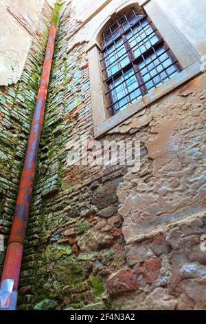 Rusty Storm Pipe of Aged House . Exterior wall with destroyed plaster . Moss growing on the bricks Stock Photo