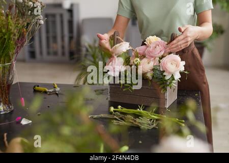 Cropped portrait of unrecognizable young woman arranging flower composition with pink peonies while working in florists workshop, copy space Stock Photo