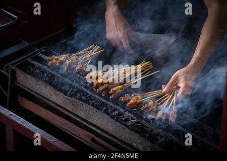 Chicken satay grill at a busy street food market Stock Photo