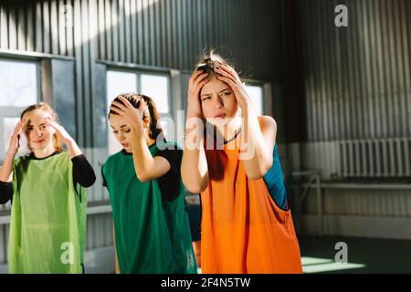 Photo of beautiful unhappy shocked women holding hands on heads, unbelievable fail, indoor game court background. Excited female team terrified of Stock Photo
