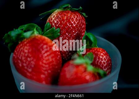 cup of ripe strawberries on black satin fabric background Stock Photo