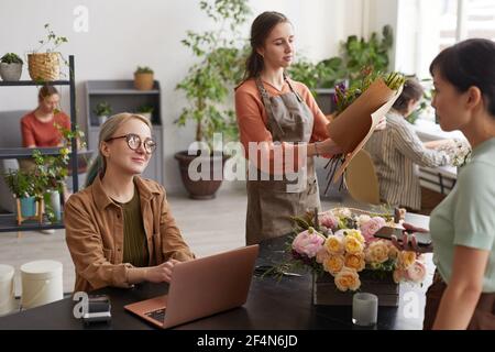 Portrait of two young female florists consulting customers while working in flower shop, copy space Stock Photo