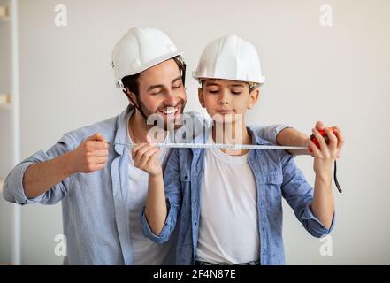 Happy dad and his son making measurements using roulette, dad teaching boy for construction working Stock Photo