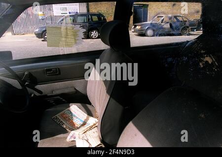 an abandoned car waits to be taken away for disposal while on the opposite side of the road is a burnt out car. southwark, s. london. photograph by mark chilvers. 22/8/00 Stock Photo