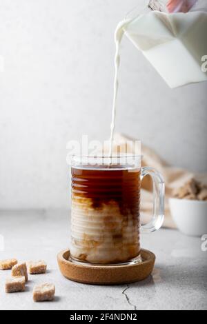cold drink with coffee and milk. glass transparent mug, on a light background. vertical position Stock Photo