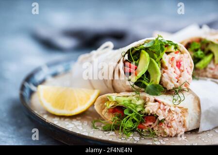 Fresh and healthy wrapped tortilla with crab salad, cucumber, avocado, pepper and green herbs Stock Photo