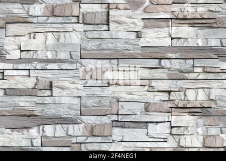Seamless texture of bricks on the wall in the form of wild stone Background. Beige and brown tones with shadows and deep texture granite or marble. Stock Photo