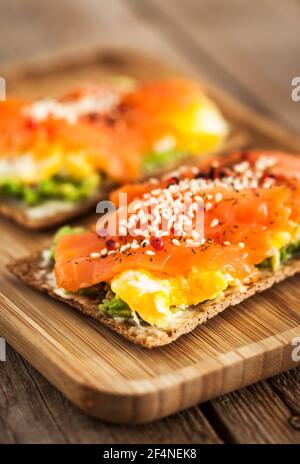 Salted salmon, scrambled eggs, avocado and cream cheese rye crisp toast Stock Photo