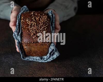Traditional Russian rye Borodino bread. Female baker holds home made artisan organic bread fresh from . Homemade sourdough bread. Food preparation. Stock Photo