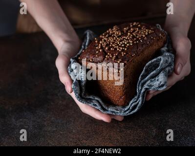 Traditional Russian rye Borodino bread. Female baker holds home made artisan organic bread fresh from . Homemade sourdough bread. Food preparation. Stock Photo